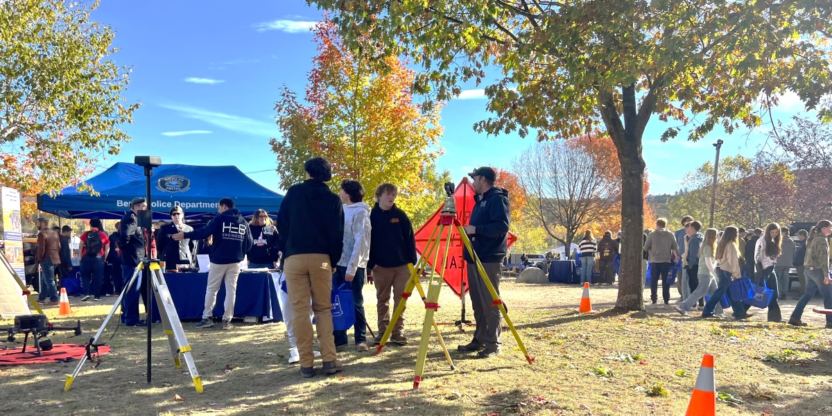 Students standing outside with land surveying equipment.