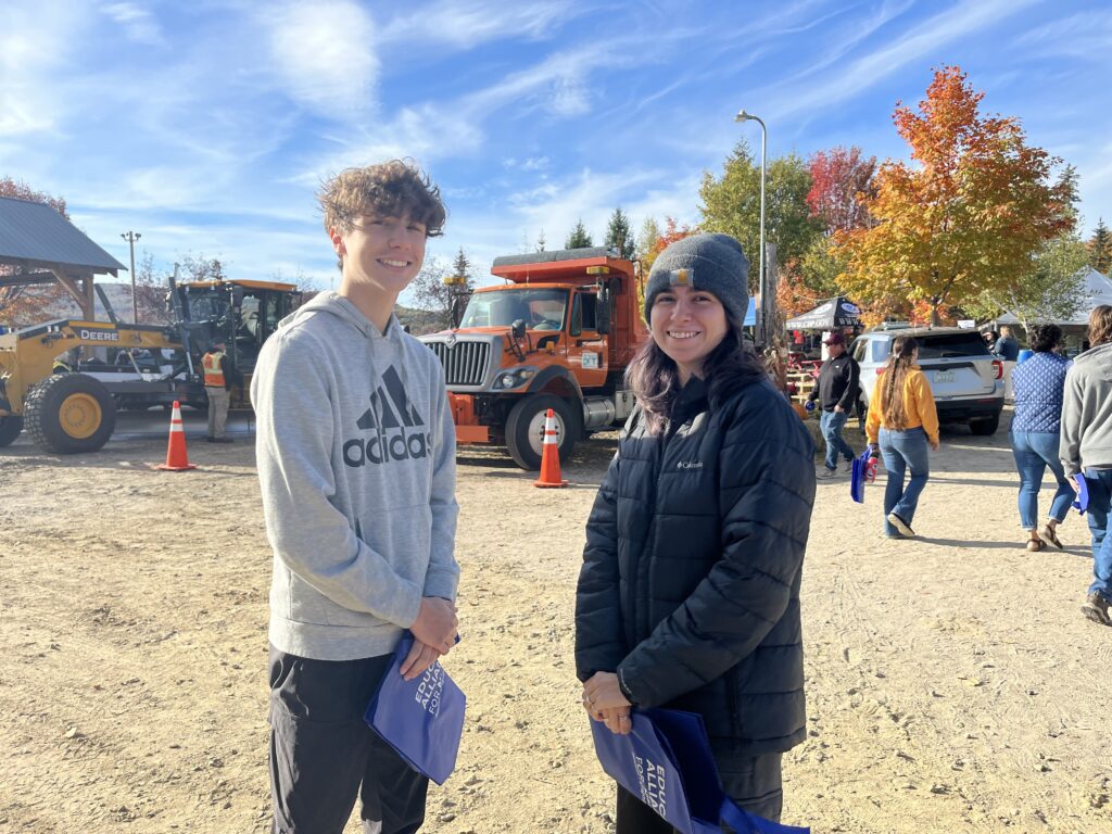Students smiling outside at the career fair with trucks in the background.